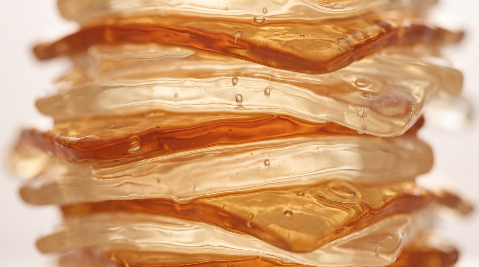 Makroaufnahme durchscheinender, geschichteter Gel-Strukturen in Amber- und Cremetönen