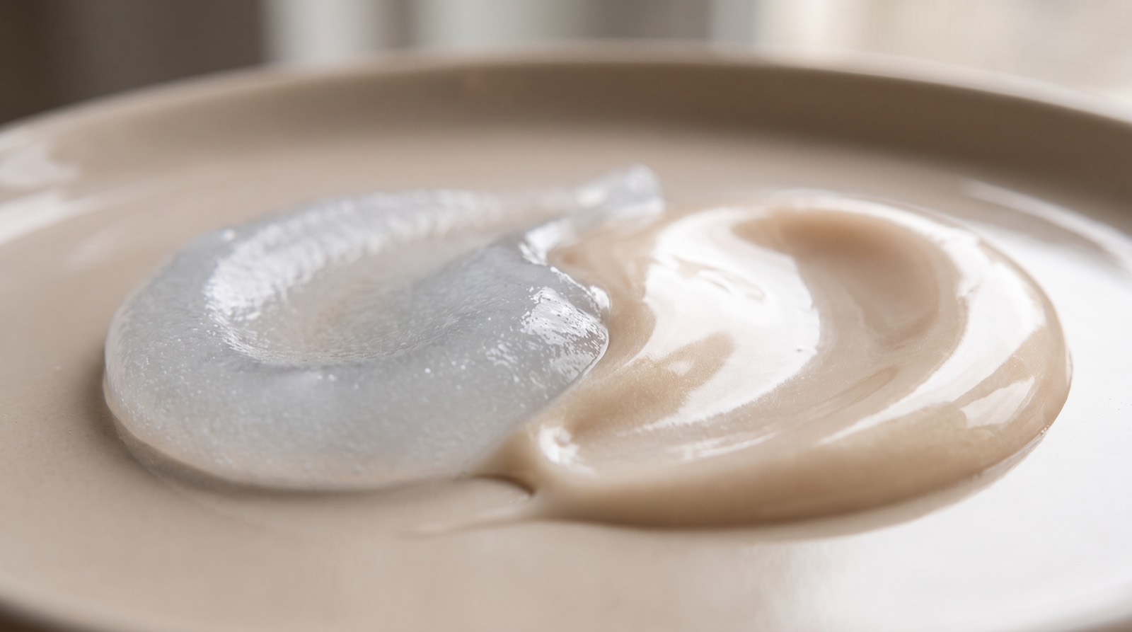 Makroaufnahme zweier ineinanderlaufender Texturen — mattes Gel und seidige Creme